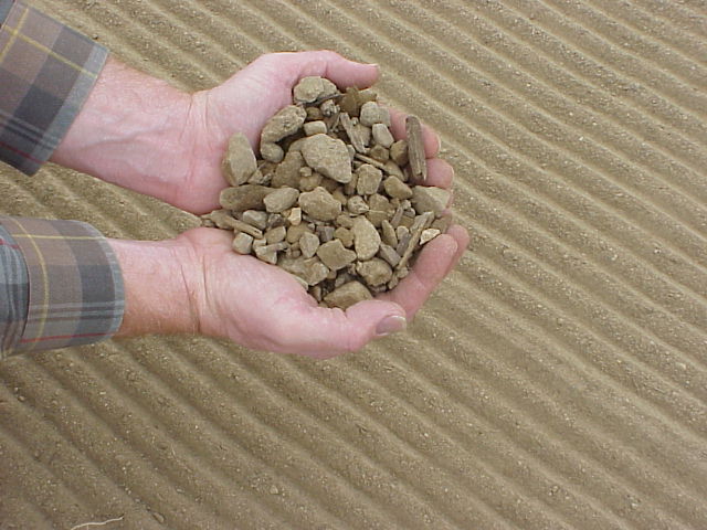 hands holding stones and groomed path of soil